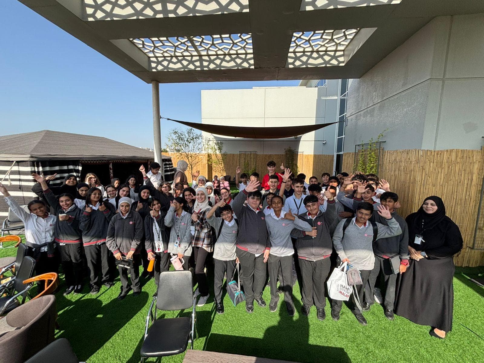 A large group of students waving at the camera during a school visit